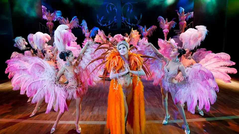 Cultural Show and Cabaret Show in Thailand: Cabaret finale at Simon Cabaret featuring center performer in vibrant orange and gold with ensemble dancers in pink feather costumes