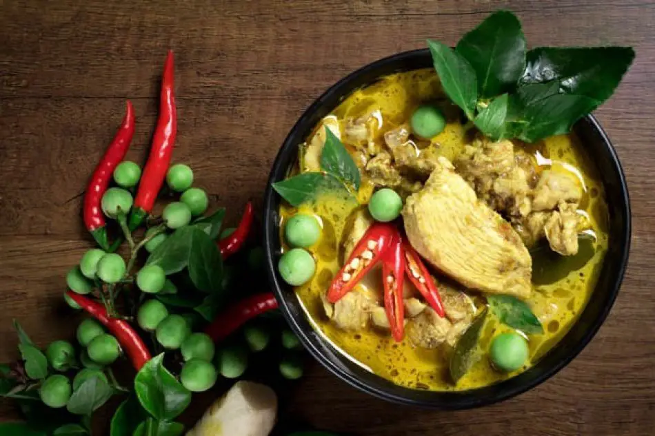 Thai food: Traditional Thai green curry with tender chicken, Thai eggplant, red chilies, and fresh basil leaves"