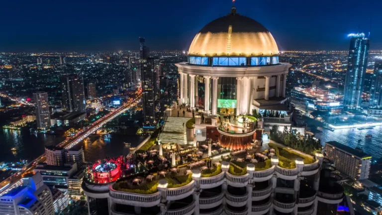 Thailand Luxury Getaway: Rooftop bar with golden dome overlooking Bangkok's illuminated skyline at night