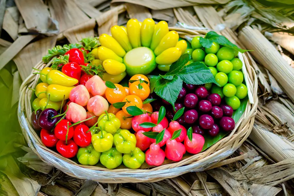 Thai Snacks: Miniature Thai fruit-shaped sweets made from mung bean paste, glossy and colorful in a traditional basket.