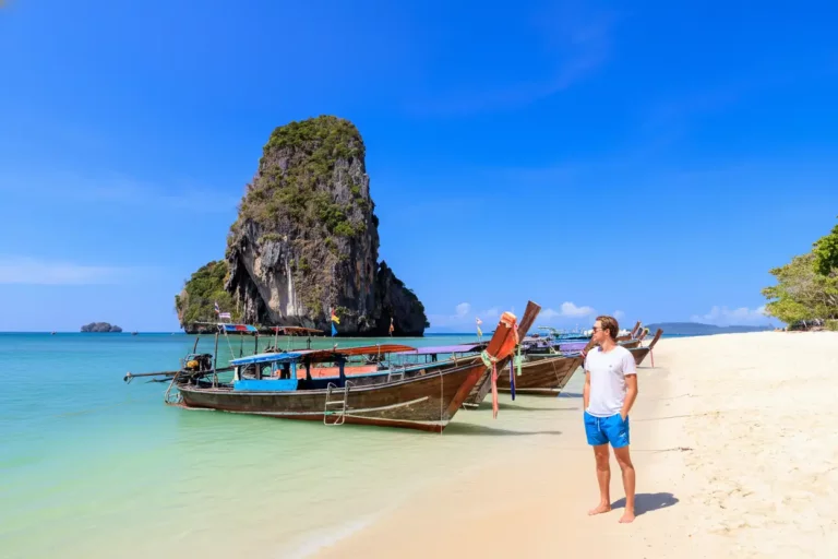 Solo traveler enjoying the safety and beauty of Thailand's beaches with longtail boats
